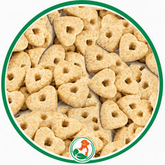 Pale Confetti Hearts dog treats with small center holes in a green-bordered circular close-up.